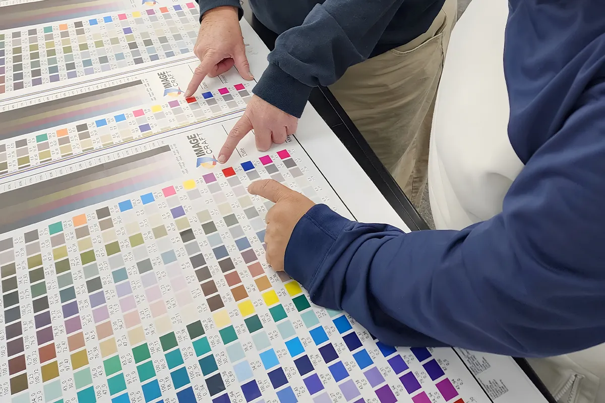 Prepress team looking and pointing at a pantone color chart.