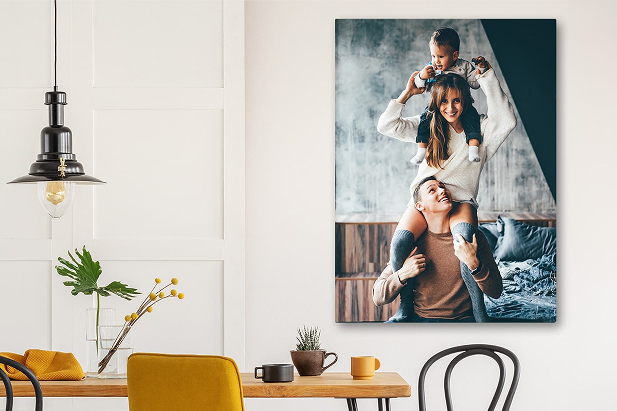 Warm and inviting dining area with a large canvas photo depicting a joyful family moment, where a smiling child sits atop a parent's shoulders, capturing a candid and affectionate family portrait, enhancing the cozy home atmosphere.