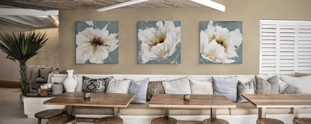 Series of artwork featuring white petal flowers hung in a cozy rustic restaurant.