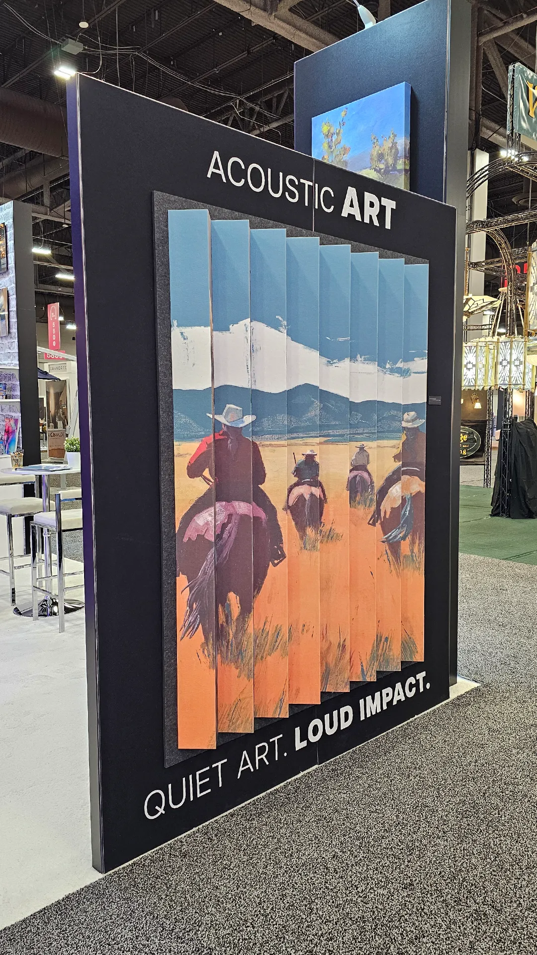 Acoustic art display featuring layered printed panels with western landscape artwork and horseback riders at the Image Craft trade show booth.