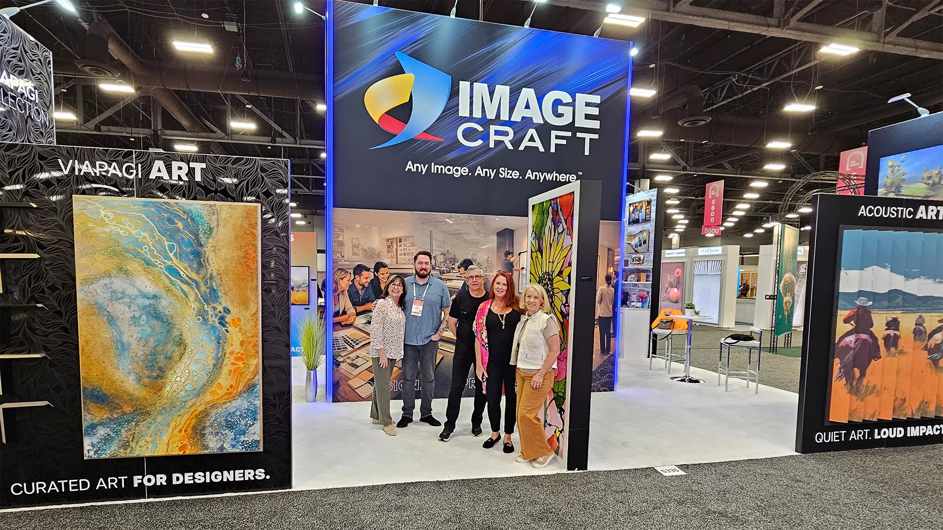 Image Craft team members standing inside the company’s trade show booth featuring acoustic art, curated artwork, and large-format display graphics at an industry expo.