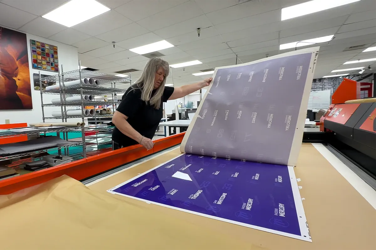 Image Craft production specialist inspecting a large-format print on a sublimated printer before producing custom Chromaluxe panels for a Phoenix Mercury signage project.
