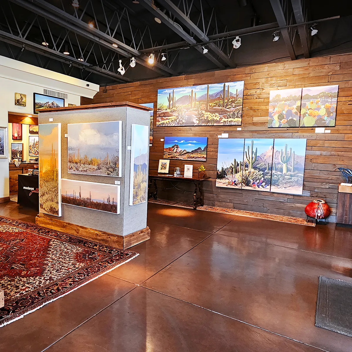 Large-format fine art prints displayed throughout a professional art gallery, showcasing landscape paintings on canvas.