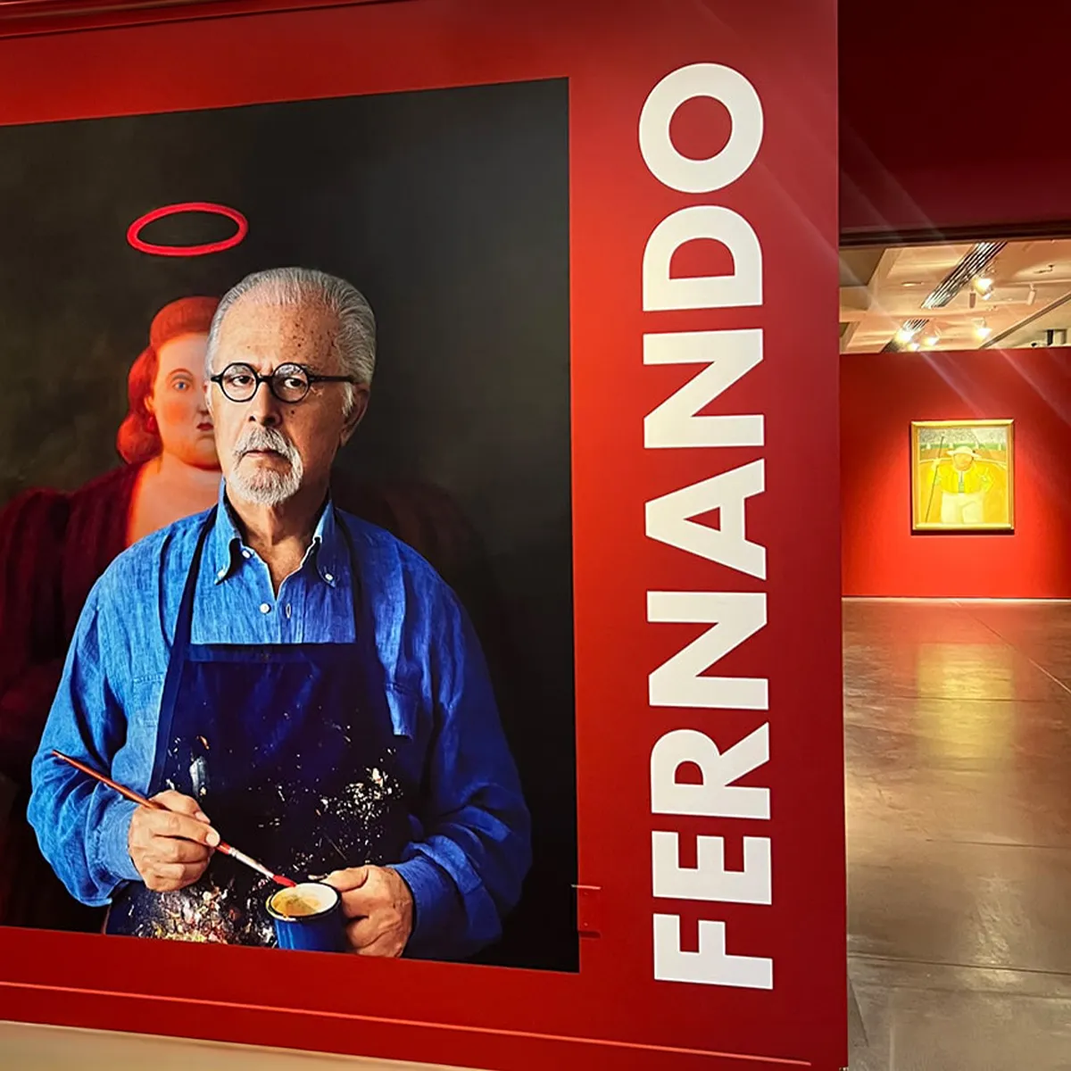 Large portrait wall graphic and dimensional lettering installed inside a museum exhibition space with artwork on display.