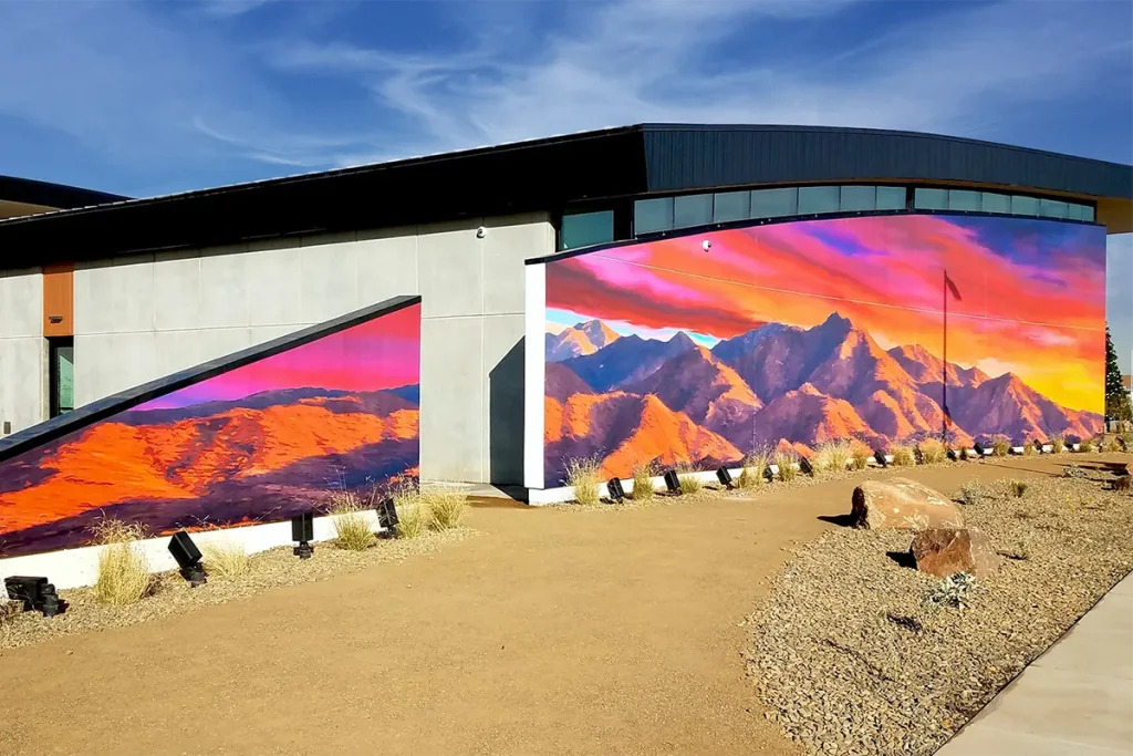 Colorful desert mountain landscape mural installed across an exterior commercial building